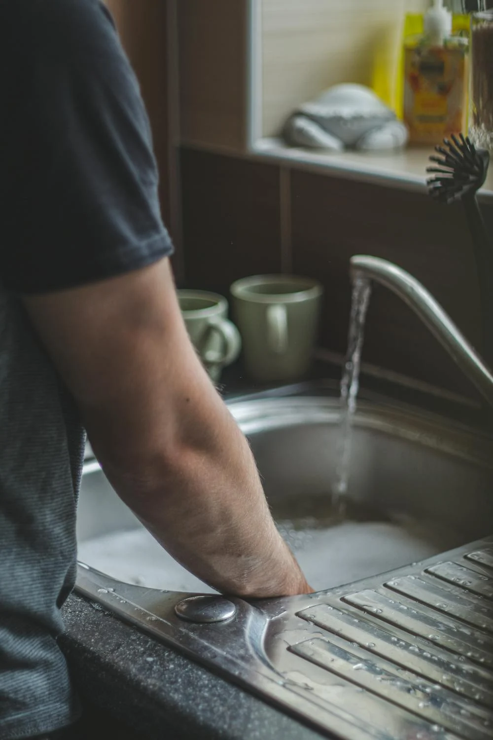 person washing using the sink with clogged drain