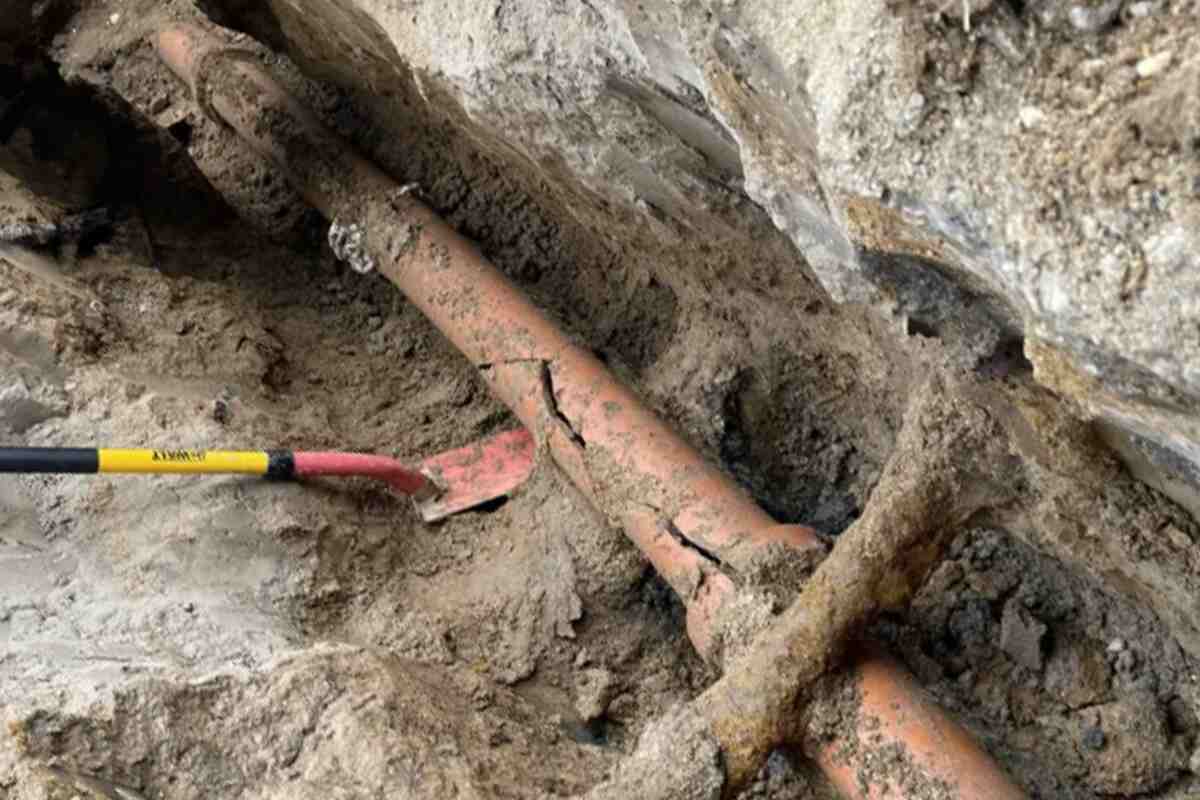 Close-up of a broken sewer line in an open dirt trench, representing the dangers of unresolved sewer pipe damage.